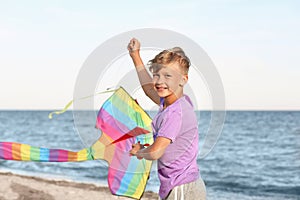 Little boy flying kite near sea