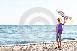 Little boy flying kite near sea