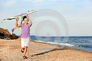 Little boy flying kite near sea