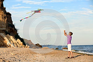 Little boy flying kite near sea