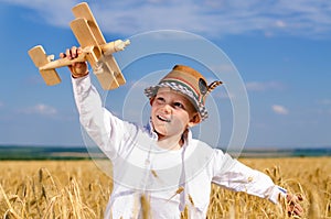 Little boy flying a toy plane in a wheat field