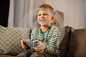 Little boy with gamepad playing video game at home