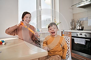 Little boy with genetic disorder laughing out loud while his mother blowing soap bubbles