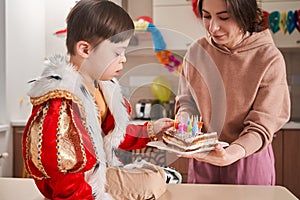 Little boy with genetic disorder sitting at the table and examining his birthday cake