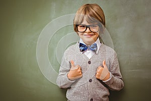 Little boy gesturing thumbs up against blackboard