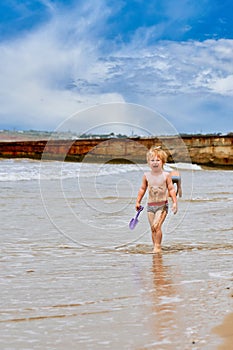 A little boy gets dirty in mud and walks crying along the beach