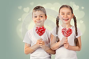 Little boy and girl with candy red lollipop in heart shape. Valentine`s day art portrait.