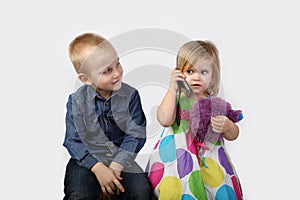 Little boy and girl with cell phone on gray