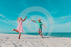 Little boy and girl dance at beach, kids enjoy vacation at sea