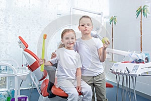 Little boy and a girl in dentist`s office. Children play dentist, hold a toothbrush and an apple in their hands.