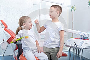 Little boy and a girl in dentist`s office. Children play dentist, hold a toothbrush and an apple in their hands.