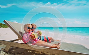 Little boy and girl drinking coconut on beach vacation