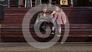 Little boy and girl eat ice-cream in wafer cones on bench