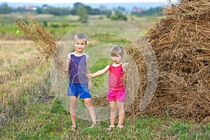 Little boy and girl on field near haystack
