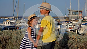 Little boy and girl in hats hold hands and play