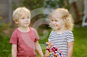 Little boy and girl having fun during walk. Happy kids with pinwheel