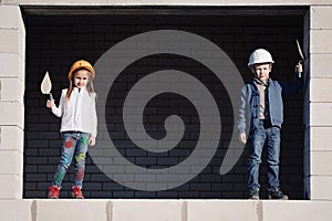 Little boy and girl in helmets build house