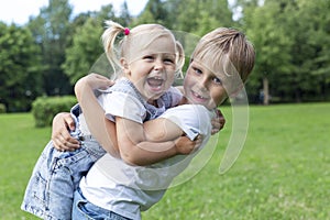 Little boy and girl laughing and hugging in a summer park. Love and tenderness in family and friendship