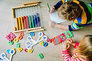 Little boy and girl learn to write and calculate numbers