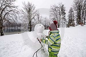 Little boy or girl making a snowman