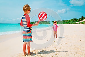 Little boy and girl play beach tennis on beach vacation
