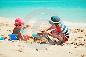 little boy and girl play with sand on beach
