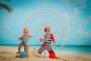 Little boy and girl play with sand building castle on beach
