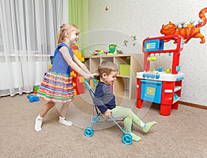 Little boy and girl play with toy stroller at home