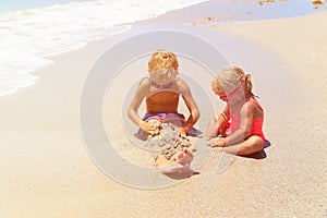 Little boy and girl play with water on beach