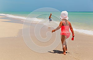 little boy and girl play with water on beach