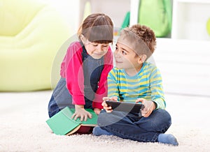 Little boy and girl playing or reading from tablet