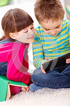 Little boy and girl playing or reading from tablet