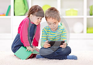 Little boy and girl playing or reading from tablet