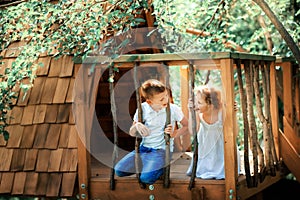 Little boy and girl playing in treehouse at forest park, Active kids on playground, Child enjoying activity in a climbing