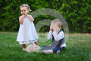 Little boy with the girl and rabbit playing in the grass