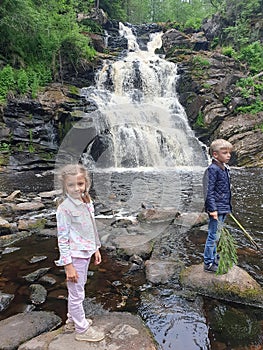 Little boy and girl relaxing and enjoying beautiful view on vacation hiking trip at waterfall. Travelling with kids concept