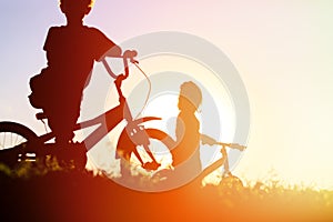 Little boy and girl riding bikes at sunset