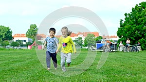 A little boy and a girl run barefoot on the grass. The concept of children's friendship and happy childhood