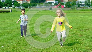 A little boy and a girl run barefoot on the grass. The concept of children's friendship and happy childhood