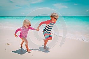 Little boy and girl run at beach, kids play on vacation