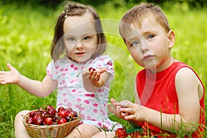 Little boy and girl sit on grass and eat