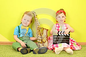 Little boy and girl sitting at a bright green