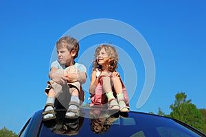 Little boy and girl sitting on car roof