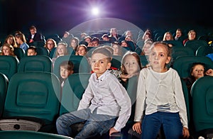 Little boy and girl sitting in the cinema hall.