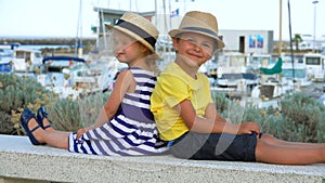 Little boy and girl sitting on a pier Yacht Club