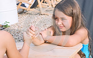 Little boy and girl sitting at table at summer beach and arm wrestling. Funny games for summer vacations.