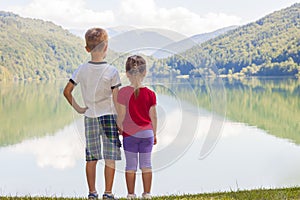 Little boy and girl standing holding hands on the bank of a lake