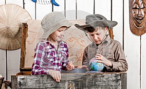 Little boy and girl study globe in big chest