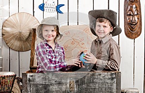 Little boy and girl study globe in big chest