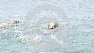 Little boy and girl swimming in ocean sea water, children having fun, playing and splashing. Summer vacation, holiday